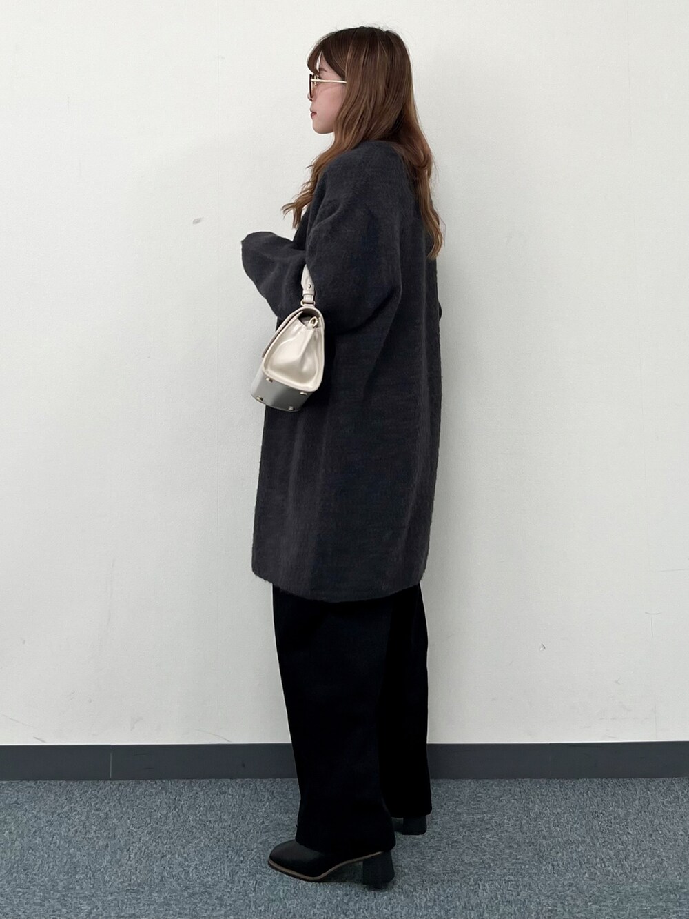 グレー系のカーディガン/ボレロ、ホワイト系のニット/セーター、ベージュ系のハンドバッグを着用したレディースの冬コーディネートの3枚目の写真