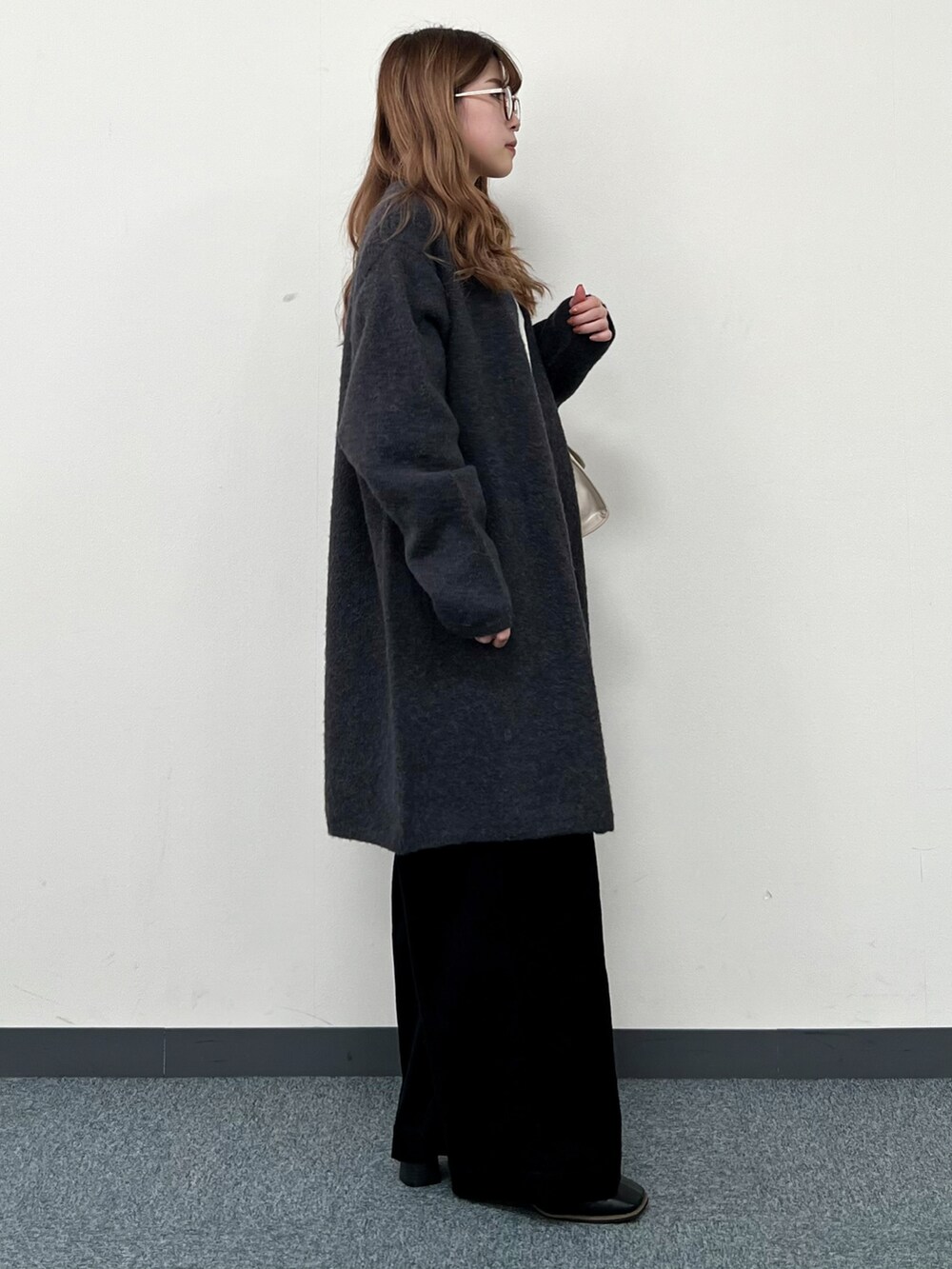 グレー系のカーディガン/ボレロ、ホワイト系のニット/セーター、ベージュ系のハンドバッグを着用したレディースの冬コーディネートの2枚目の写真