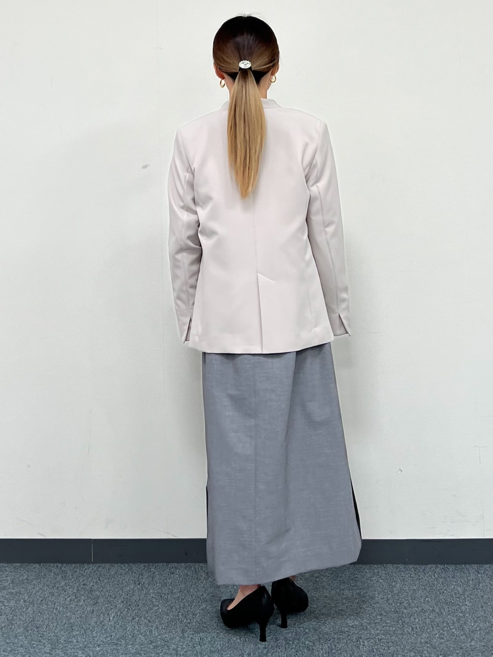 グレー系のノーカラージャケット、グレー系のワンピース、ブラック系のパンプスを着用したレディースの冬コーディネートの3枚目の写真