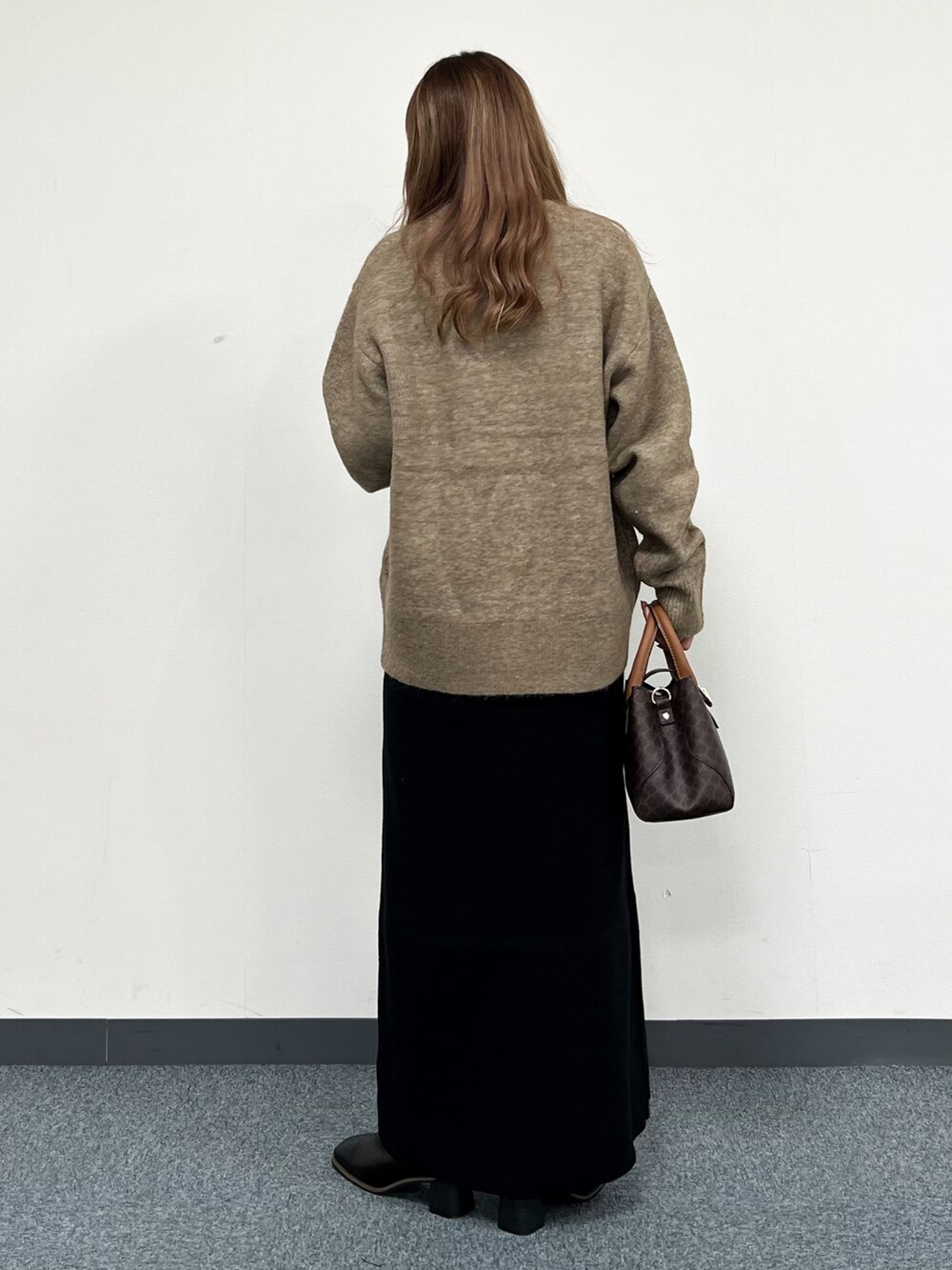 ブラウン系のショルダーバッグ、ベージュ系のニット/セーター、ブラック系のワンピースを着用したレディースの冬コーディネートの4枚目の写真