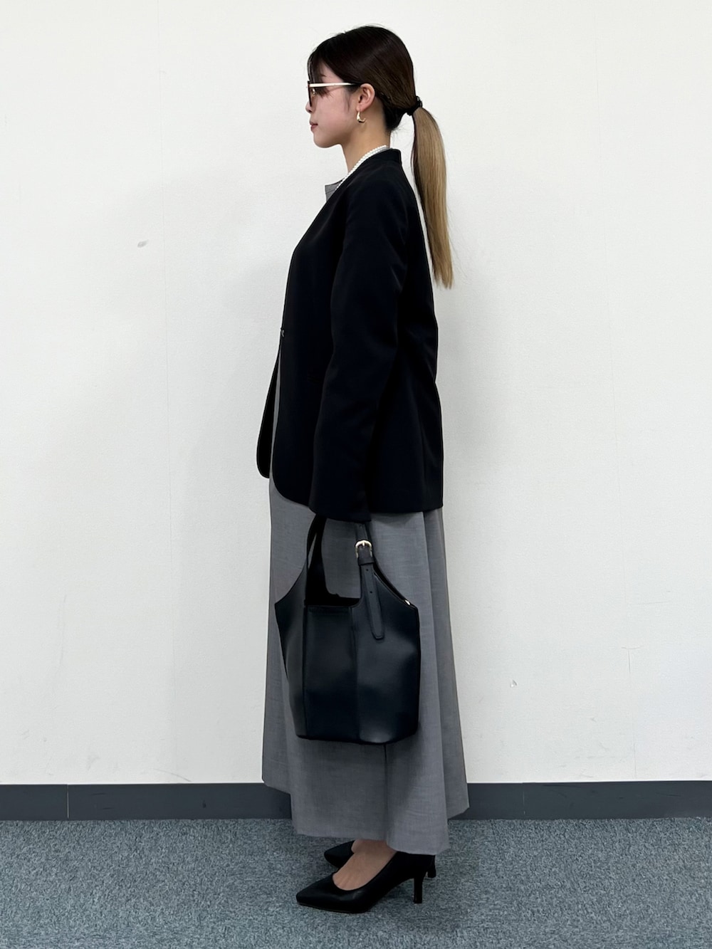 ブラック系のノーカラージャケット、グレー系のワンピース、ブラック系のトートバッグを着用したレディースの冬コーディネートの4枚目の写真