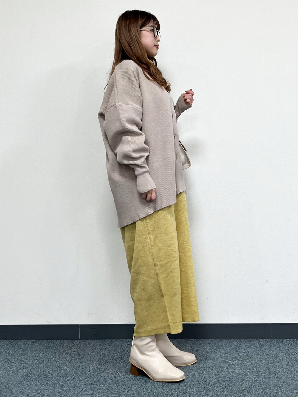 ベージュ系のカーディガン/ボレロ、ベージュ系のハンドバッグ、イエロー系のワンピースを着用したレディースの冬コーディネートの2枚目の写真