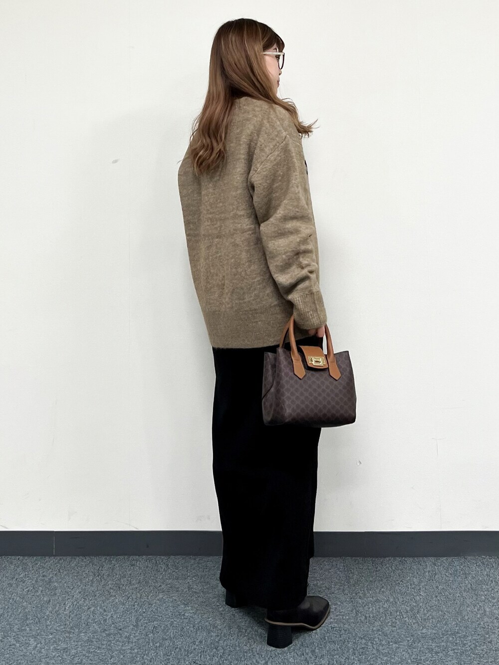 ブラウン系のショルダーバッグ、ベージュ系のニット/セーター、ブラック系のワンピースを着用したレディースの冬コーディネートの3枚目の写真