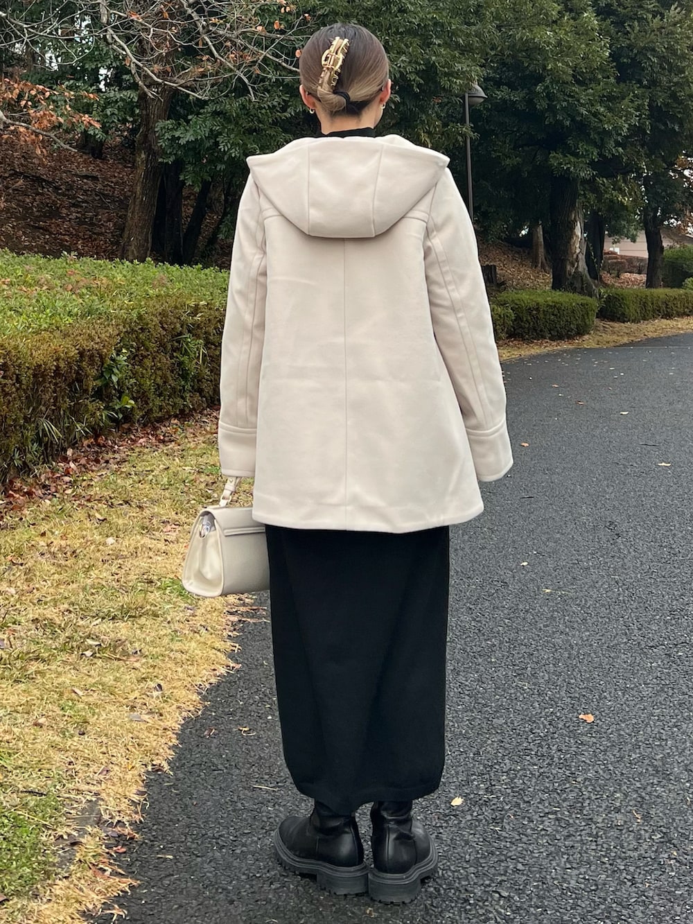 ベージュ系のその他アウター、ホワイト系のニット/セーター、ベージュ系のハンドバッグを着用したレディースの冬コーディネートの3枚目の写真