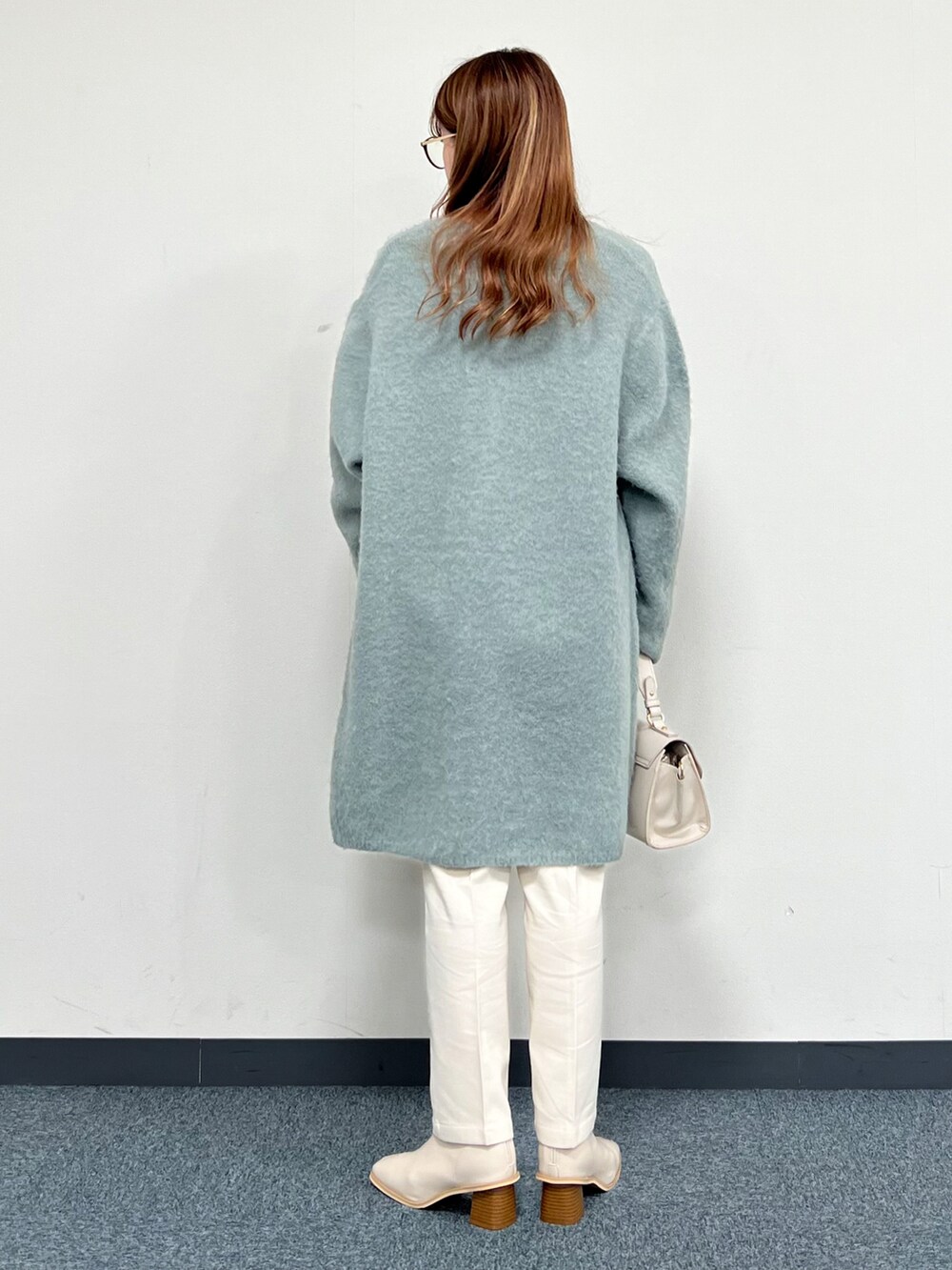 グリーン系のカーディガン/ボレロ、ベージュ系のハンドバッグ、ホワイト系のその他パンツを着用したレディースの冬コーディネートの3枚目の写真