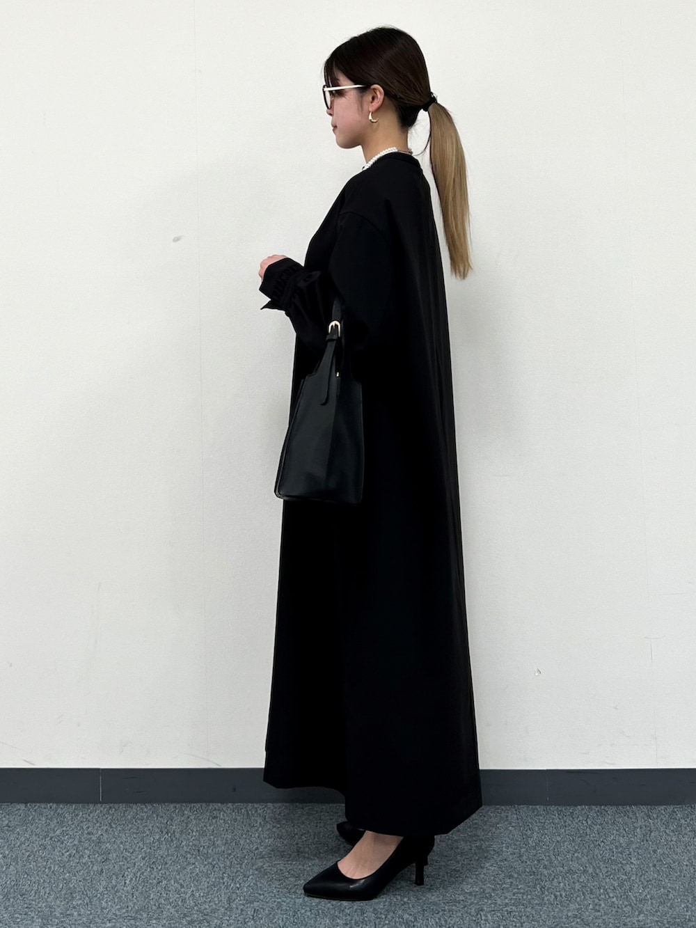 ブラック系のトートバッグ、ブラック系のワンピース、ブラック系のパンプスを着用したレディースの冬コーディネートの4枚目の写真