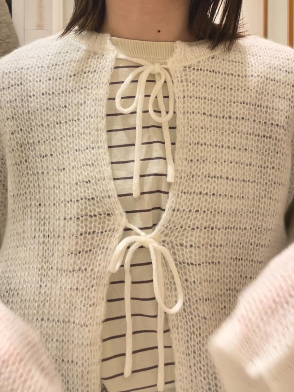 ブルー系のデニムパンツ、ホワイト系のカーディガン/ボレロを着用したレディースの冬コーディネートの4枚目の写真