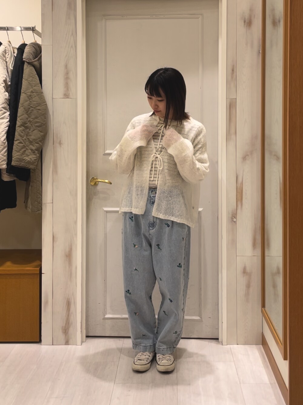 ブルー系のデニムパンツ、ホワイト系のカーディガン/ボレロを着用したレディースの冬コーディネートの2枚目の写真