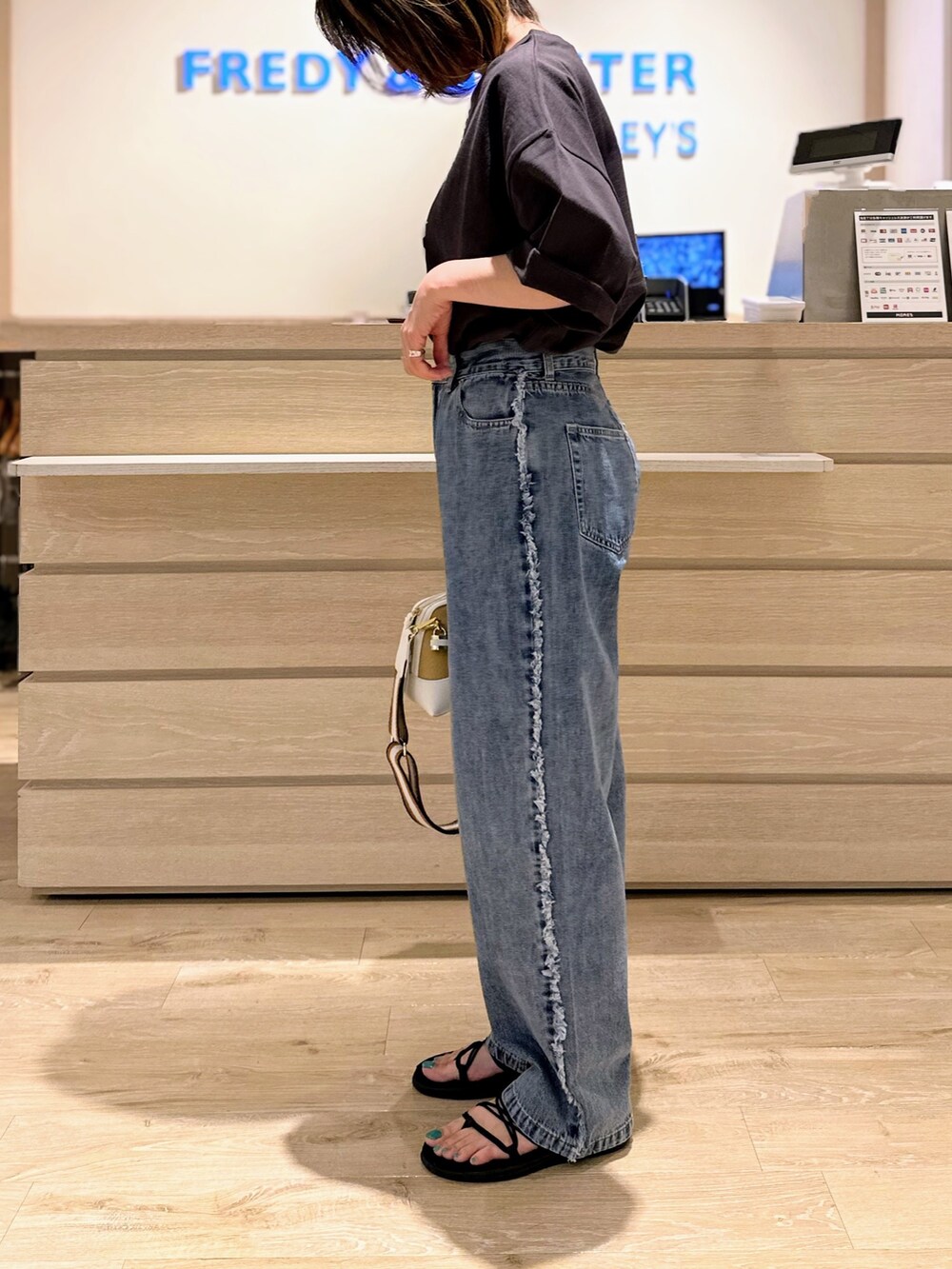 ホワイト系のショルダーバッグ、グレー系のTシャツ/カットソー、ブルー系のデニムパンツを着用したレディースの夏コーディネートの2枚目の写真