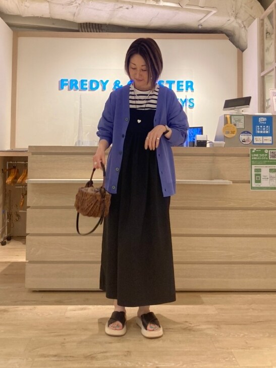 ホワイト系のTシャツ/カットソー、パープル系のカーディガン/ボレロ、ブラック系のワンピースを着用したレディースの春コーディネートの2枚目の写真