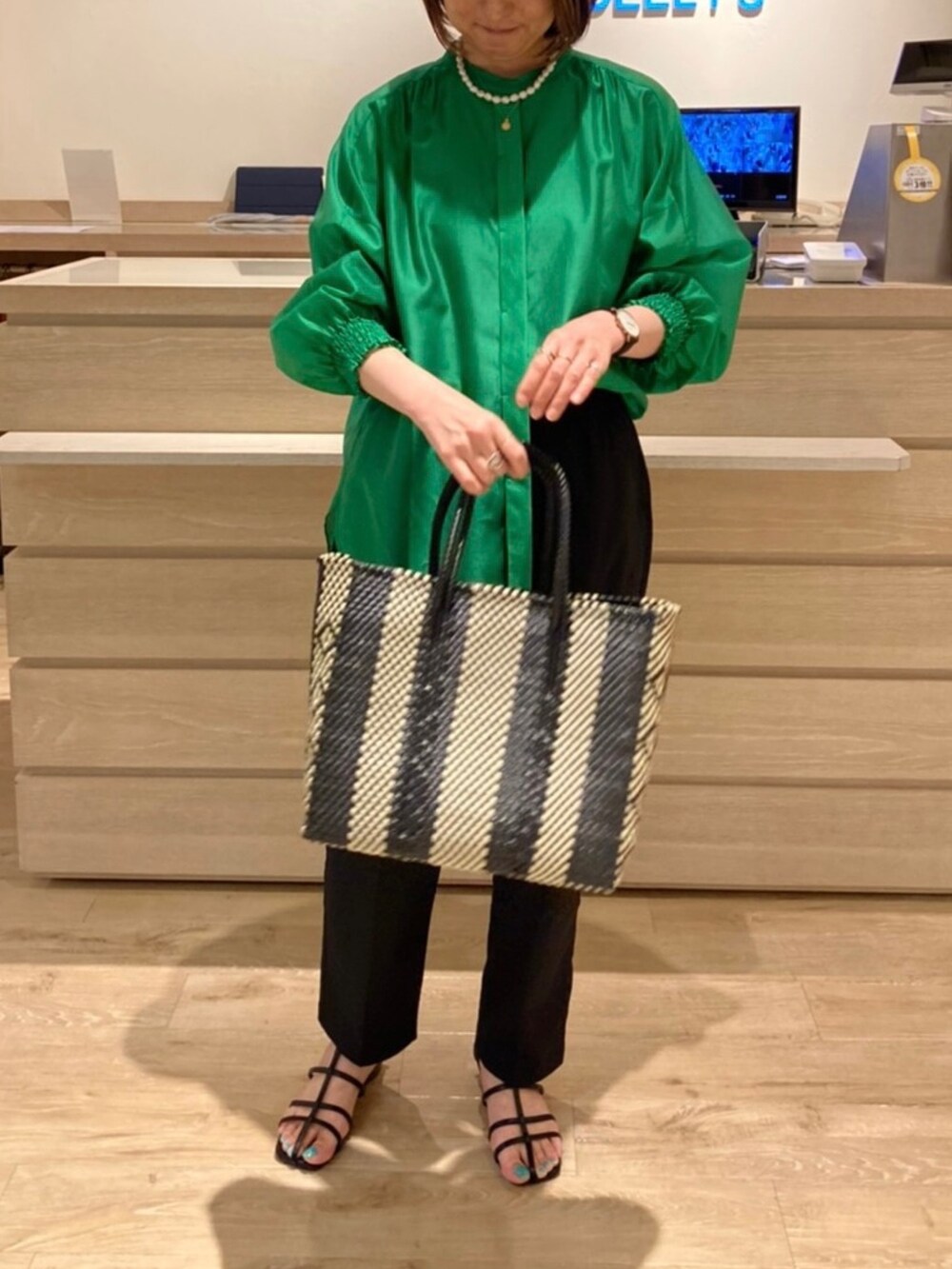 ブラック系のスラックス、グリーン系のシャツ/ブラウス、ブラック系のサンダルを着用したレディースの夏コーディネートの2枚目の写真