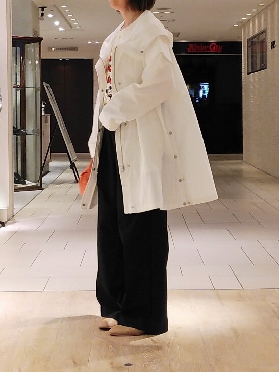 ホワイト系のブルゾン、ブラック系のスラックス、オレンジ系のトートバッグを着用したレディースの春コーディネートの2枚目の写真