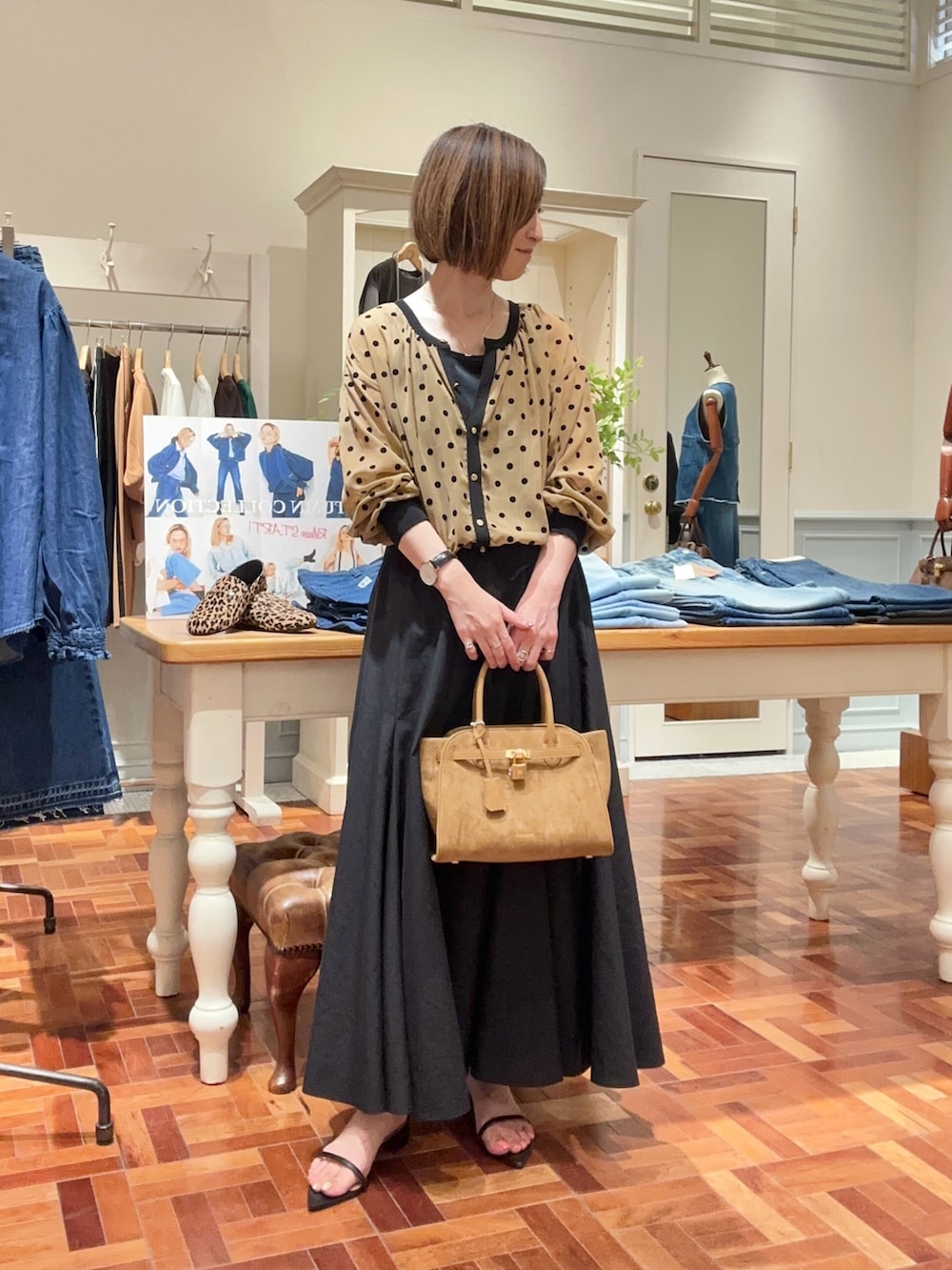 ブラック系のタンクトップ、イエロー系のカーディガン/ボレロ、ブラック系のスカートを着用したレディースの夏コーディネートの2枚目の写真