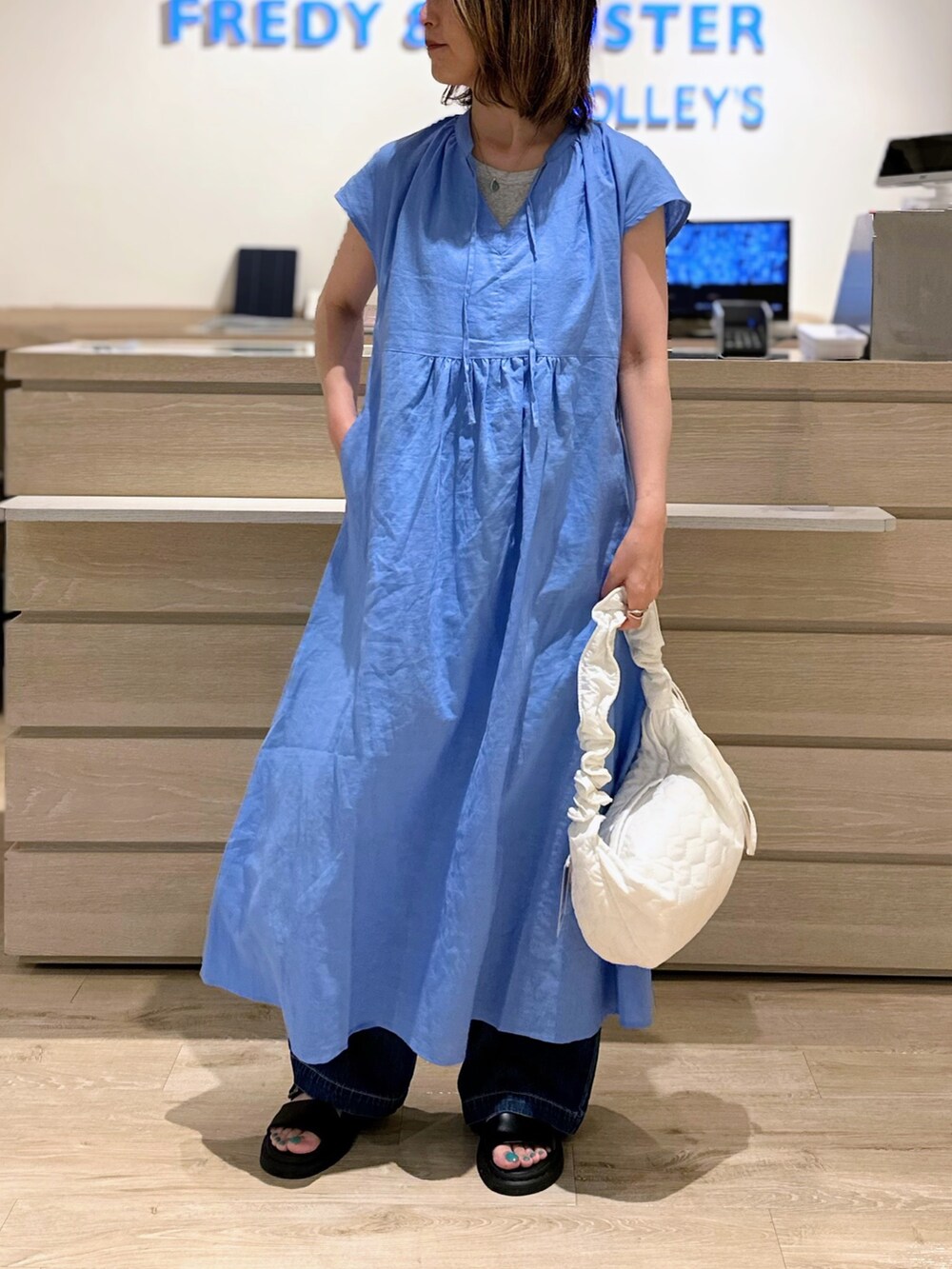 ホワイト系のショルダーバッグ、ブルー系のワンピース、ブルー系のデニムパンツを着用したレディースの夏コーディネートの2枚目の写真