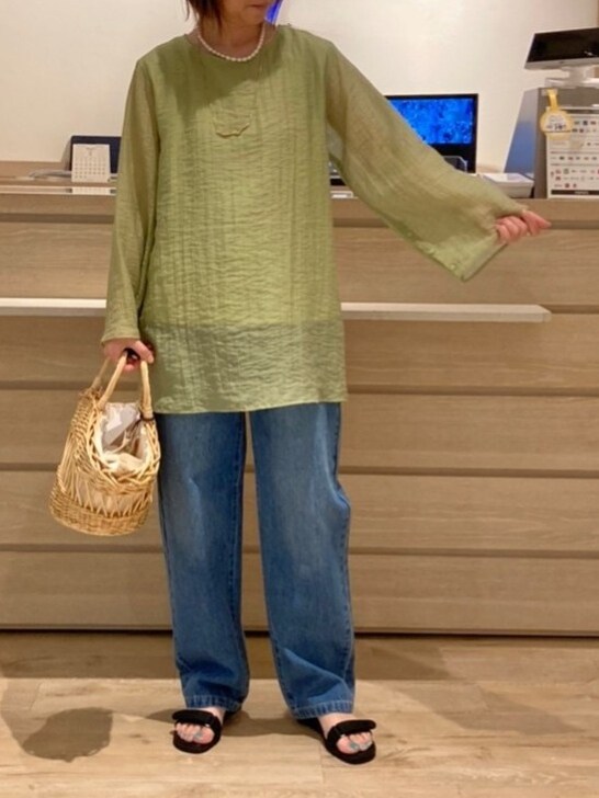 グリーン系のシャツ/ブラウス、ベージュ系のかごバッグ、ブルー系のデニムパンツを着用したレディースの春コーディネートの2枚目の写真