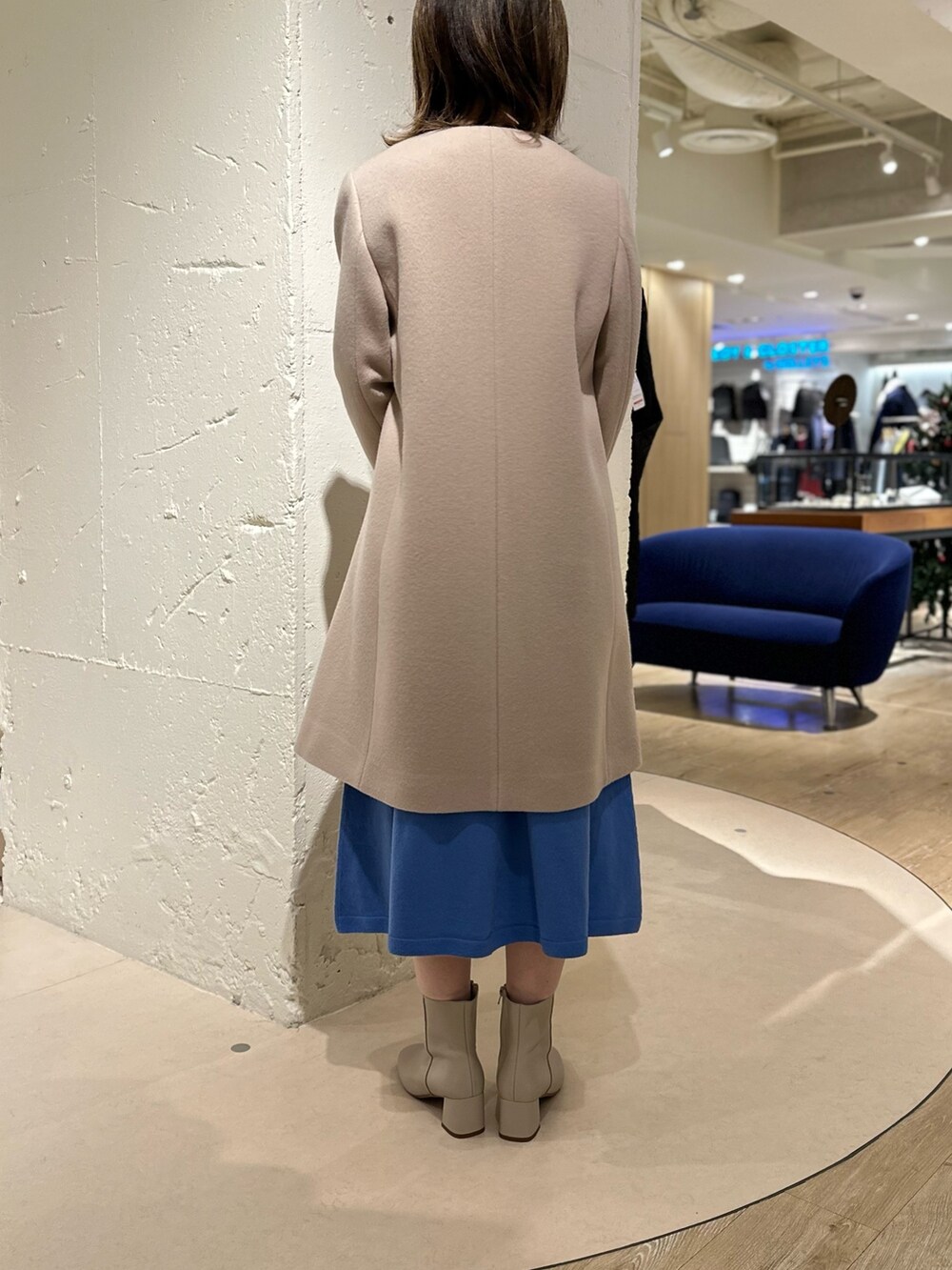 ベージュ系のショルダーバッグ、ホワイト系のブーツ、ブルー系のワンピースを着用したレディースの冬コーディネートの3枚目の写真