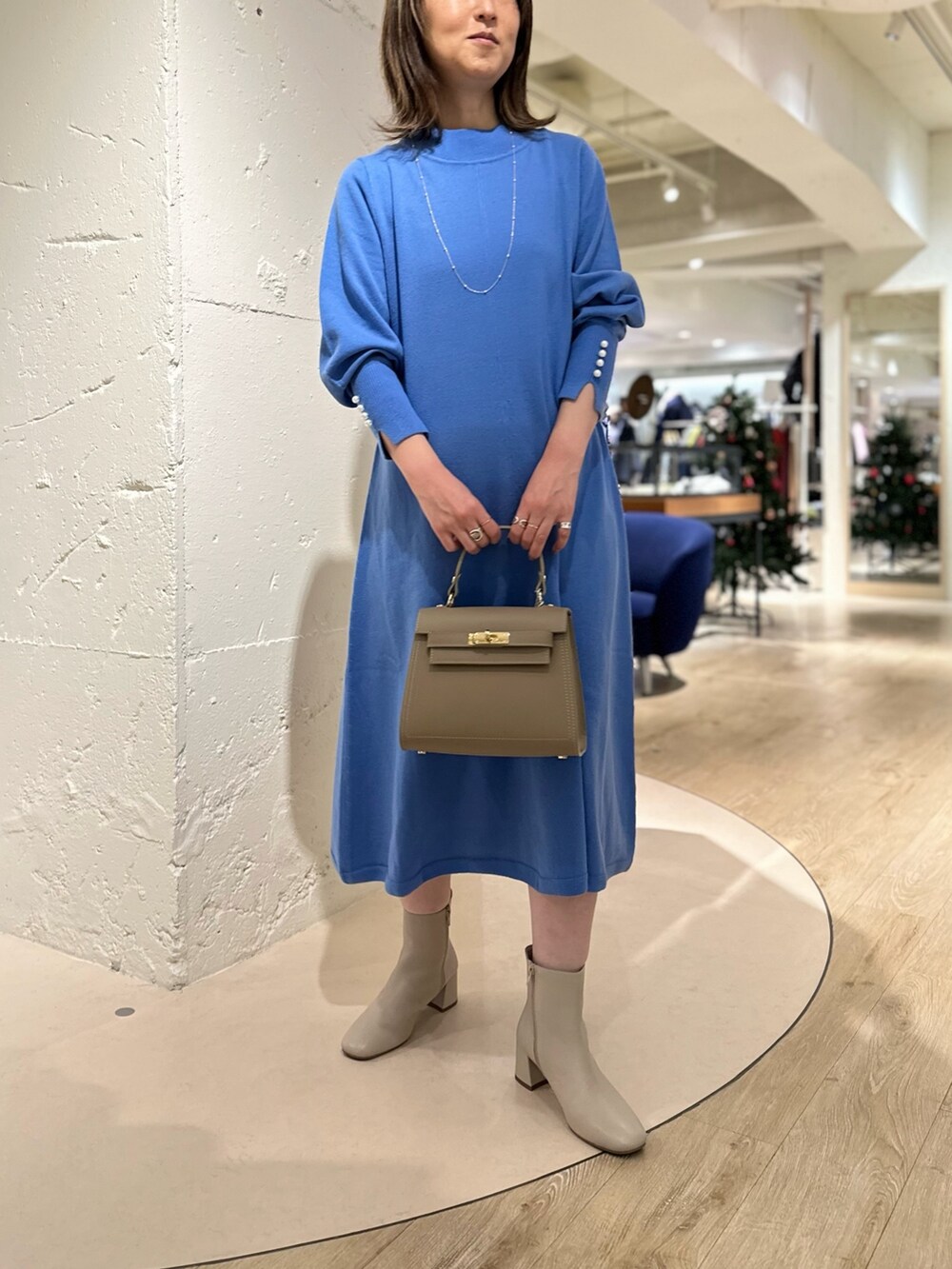 ベージュ系のショルダーバッグ、ホワイト系のブーツ、ブルー系のワンピースを着用したレディースの冬コーディネートの4枚目の写真