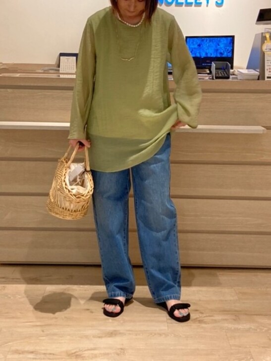 グリーン系のシャツ/ブラウス、ベージュ系のかごバッグ、ブルー系のデニムパンツを着用したレディースの春コーディネートの3枚目の写真