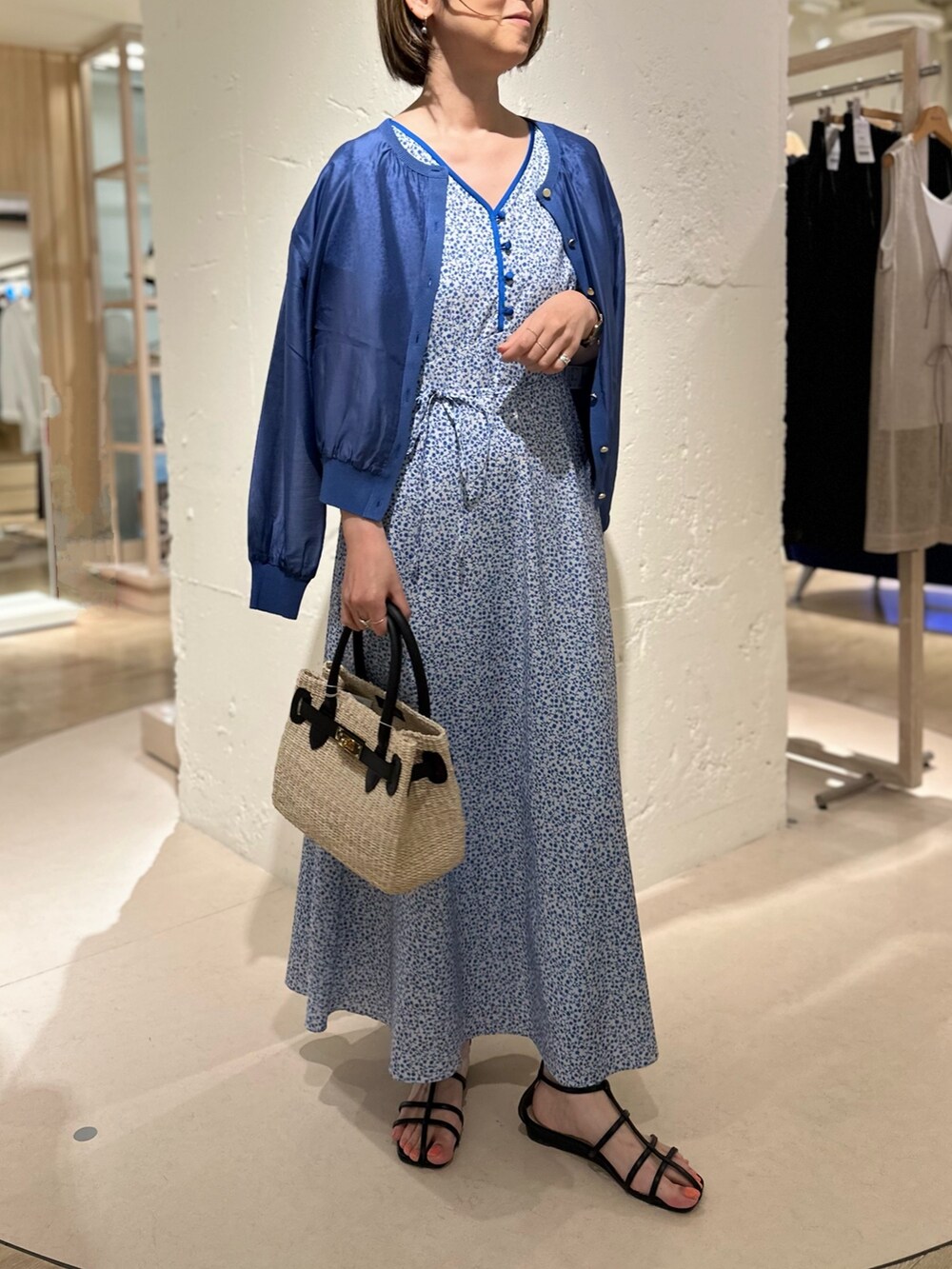 ブラック系のかごバッグ、ブルー系のカーディガン/ボレロ、ブルー系のワンピースを着用したレディースの夏コーディネートの2枚目の写真