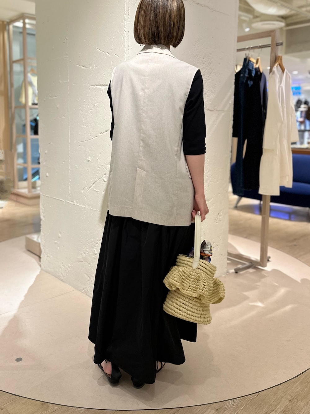 ブラック系のワンピース、ベージュ系のベスト、ベージュ系のかごバッグを着用したレディースの春コーディネートの4枚目の写真