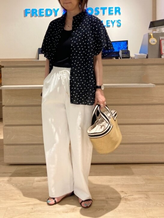 ブラック系のシャツ/ブラウス、ホワイト系のスラックス、ベージュ系のトートバッグを着用したレディースの春コーディネートの2枚目の写真