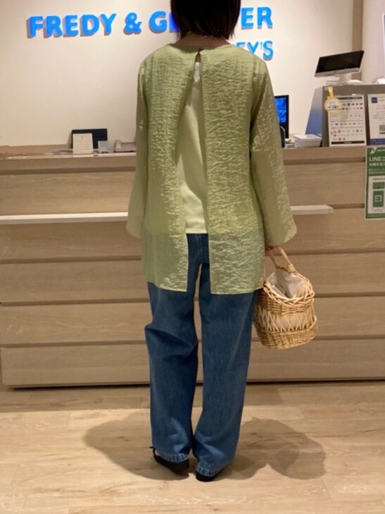 グリーン系のシャツ/ブラウス、ベージュ系のかごバッグ、ブルー系のデニムパンツを着用したレディースの春コーディネートの4枚目の写真