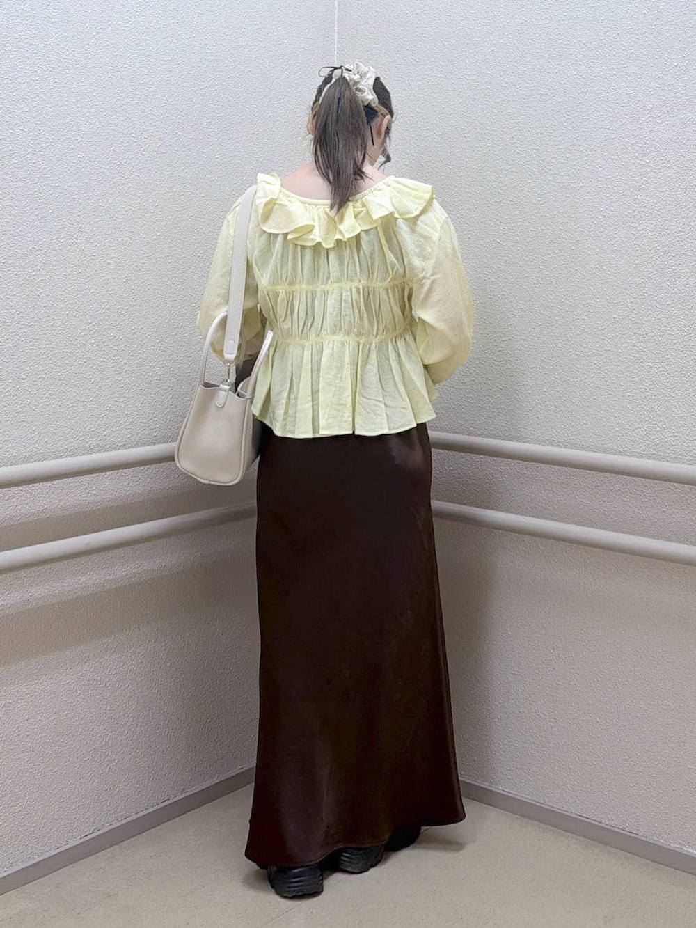 ブラウン系のスカート、ホワイト系のショルダーバッグ、イエロー系のシャツ/ブラウスを着用したレディースの春コーディネートの3枚目の写真