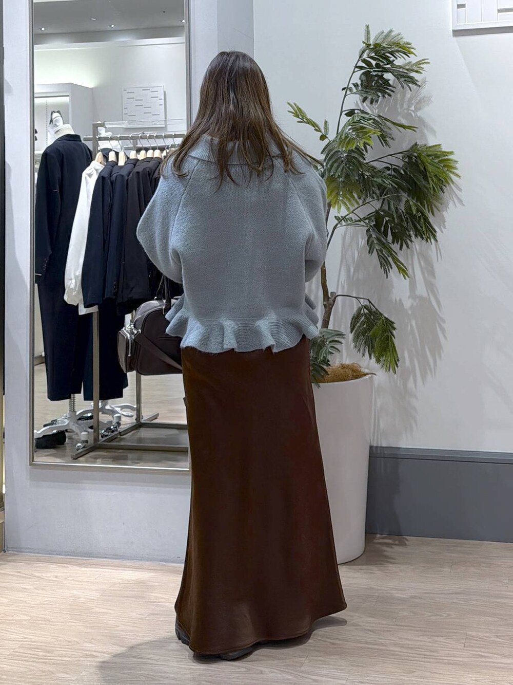 ブラック系のブーツ、ブラウン系のスカート、ブラウン系のボストンバッグを着用したレディースの冬コーディネートの5枚目の写真