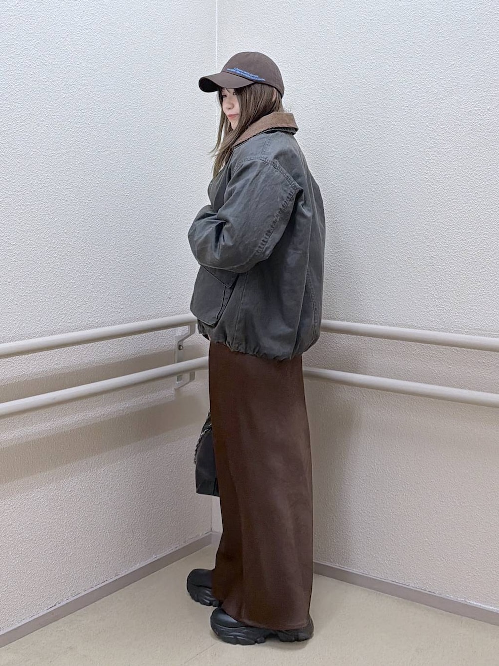 ブラック系のブーツ、ブラウン系のスカート、ブラック系のショルダーバッグを着用したレディースの冬コーディネートの2枚目の写真