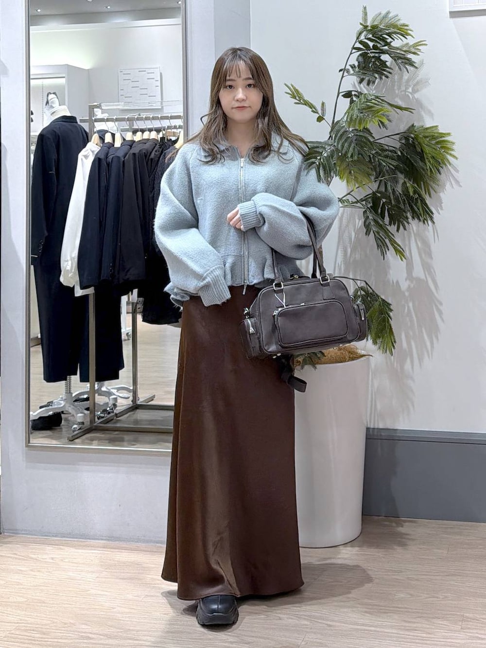 ブラック系のブーツ、ブラウン系のスカート、ブラウン系のボストンバッグを着用したレディースの冬コーディネートの2枚目の写真