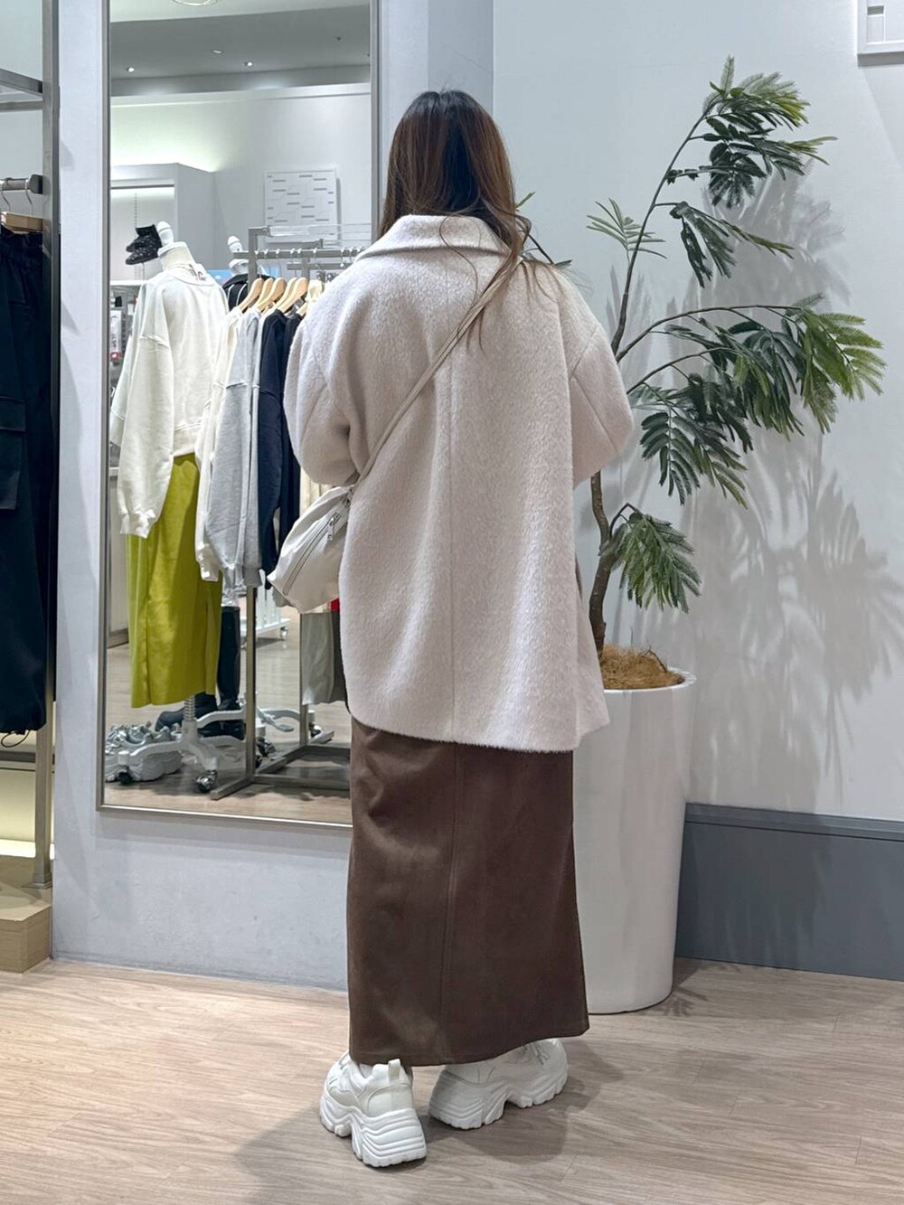 ブラウン系のスカート、ベージュ系のその他アウター、ホワイト系のスニーカーを着用したレディースの冬コーディネートの3枚目の写真