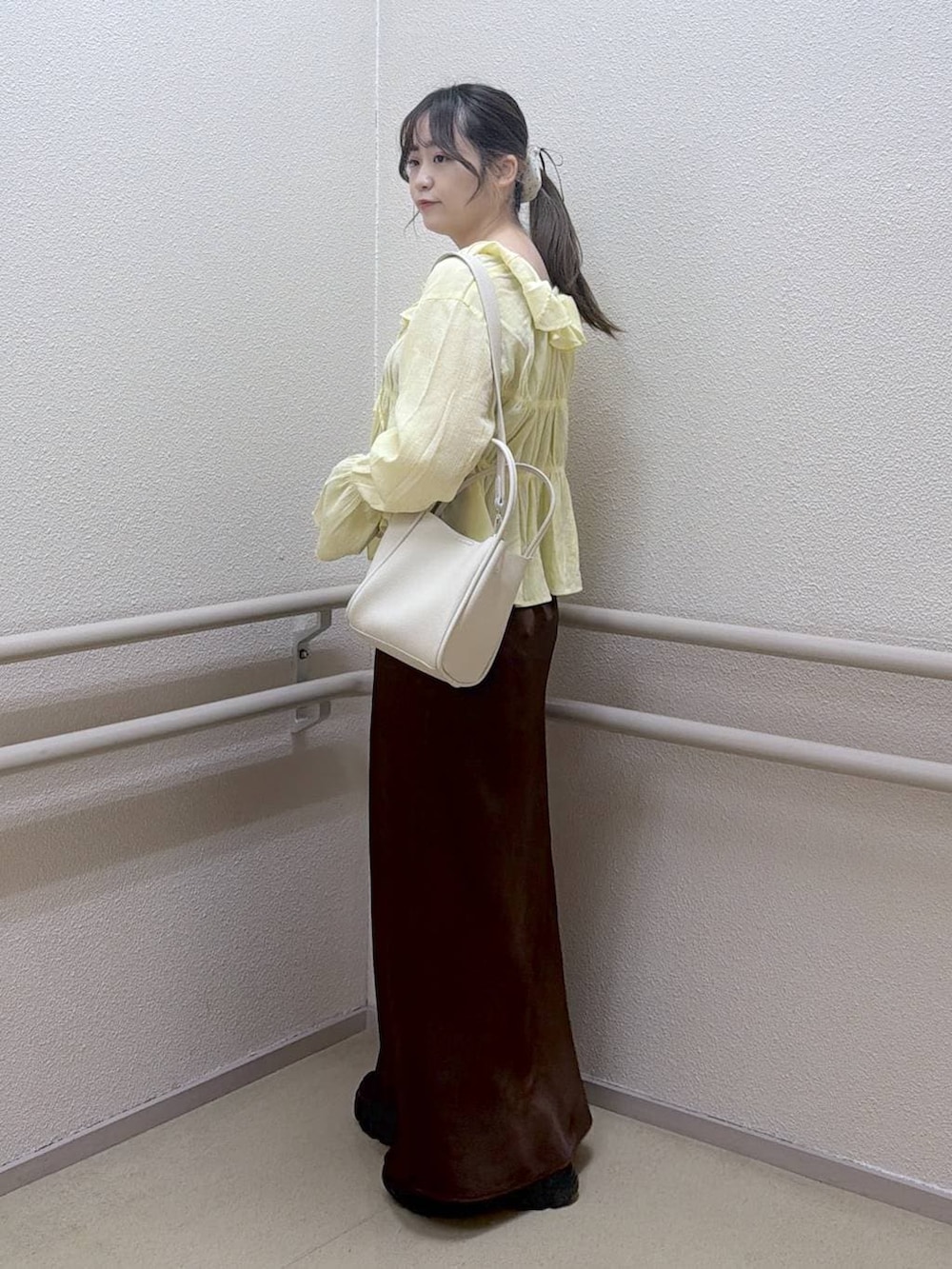ブラウン系のスカート、ホワイト系のショルダーバッグ、イエロー系のシャツ/ブラウスを着用したレディースの春コーディネートの2枚目の写真