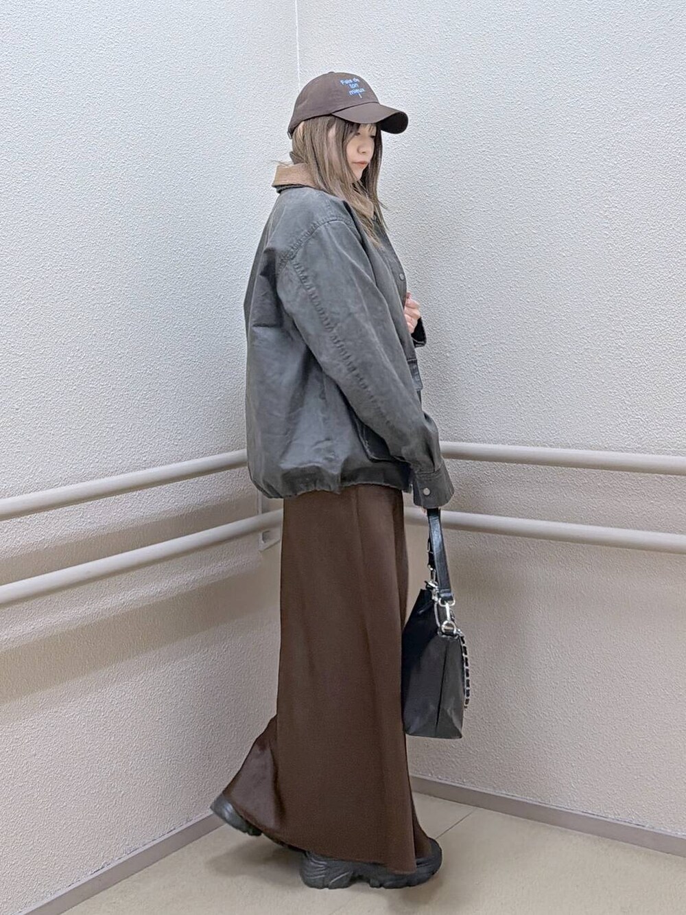 ブラック系のブーツ、ブラウン系のスカート、ブラック系のショルダーバッグを着用したレディースの冬コーディネートの3枚目の写真