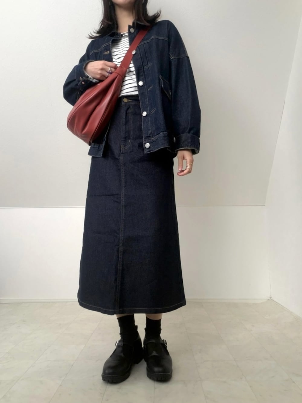 ホワイト系のTシャツ/カットソー、レッド系のショルダーバッグ、ブルー系のデニムスカートを着用したレディースの冬コーディネートの2枚目の写真