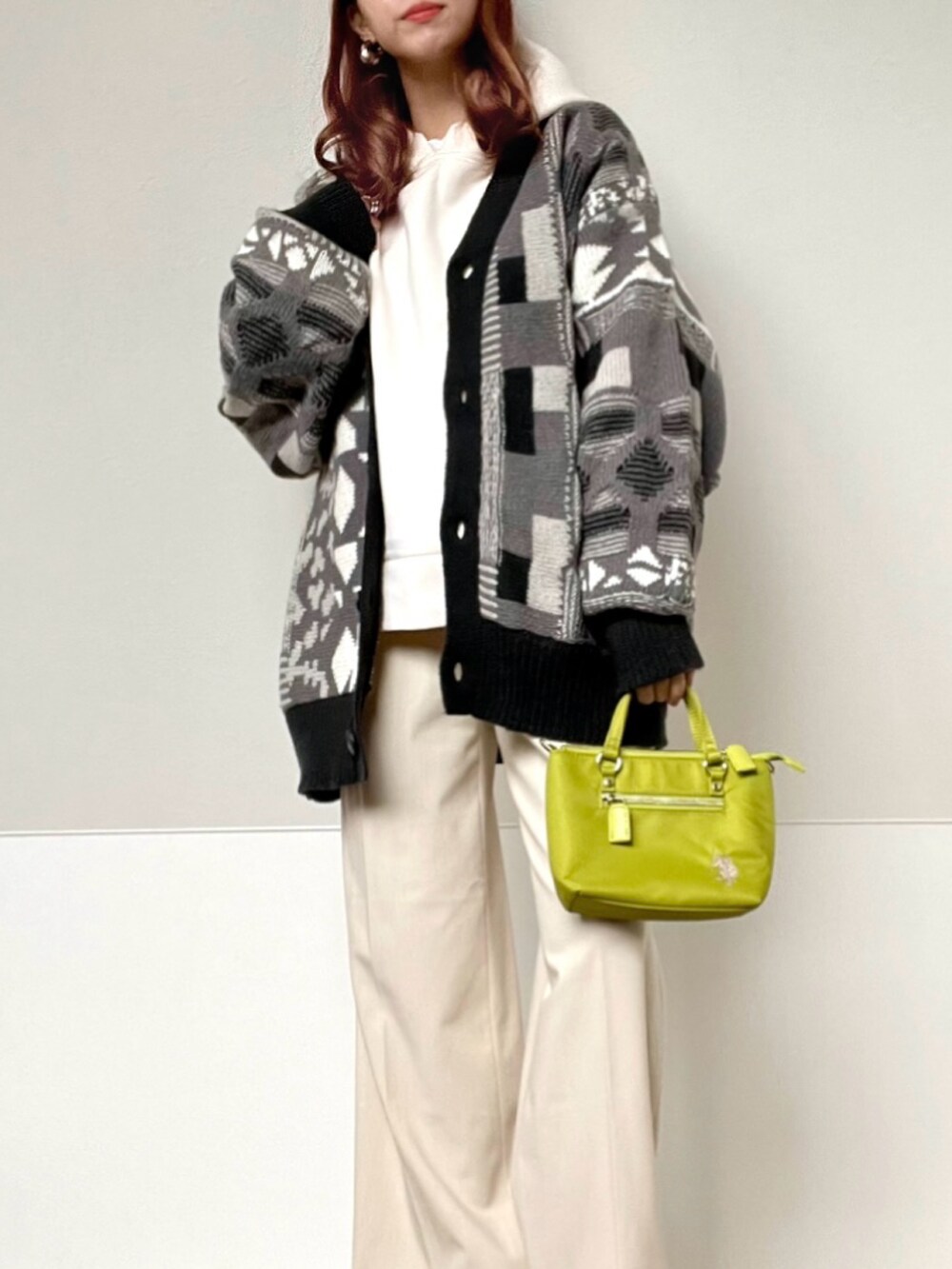 グレー系のカーディガン/ボレロ、グリーン系のショルダーバッグ、ホワイト系のスラックスを着用したレディースの秋コーディネートの2枚目の写真