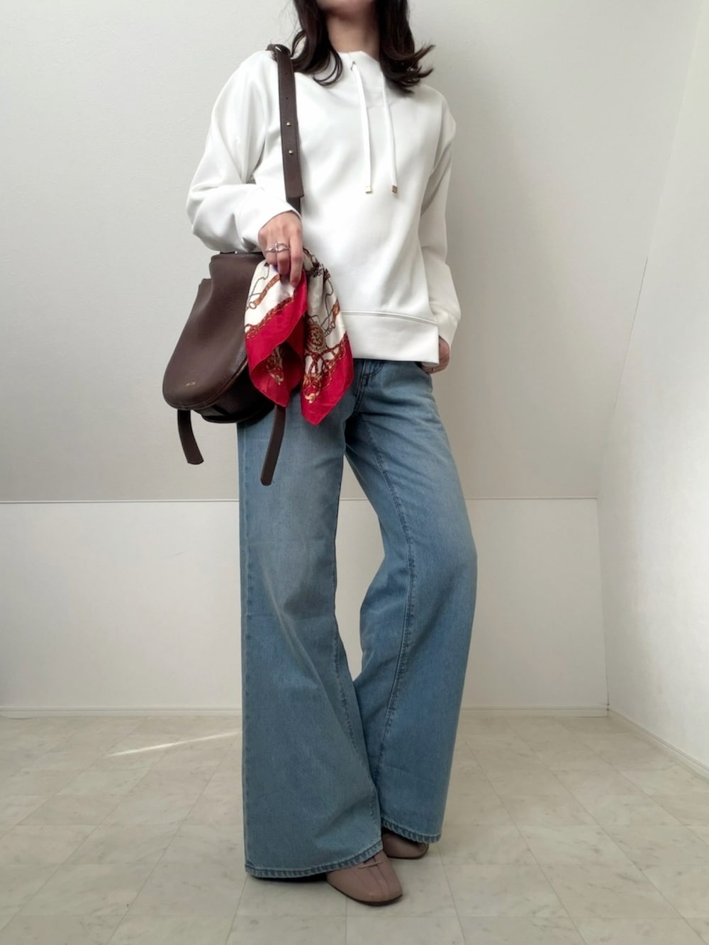 ブラウン系のショルダーバッグ、ホワイト系のスウェット、ブルー系のデニムパンツを着用したレディースの春コーディネートの2枚目の写真