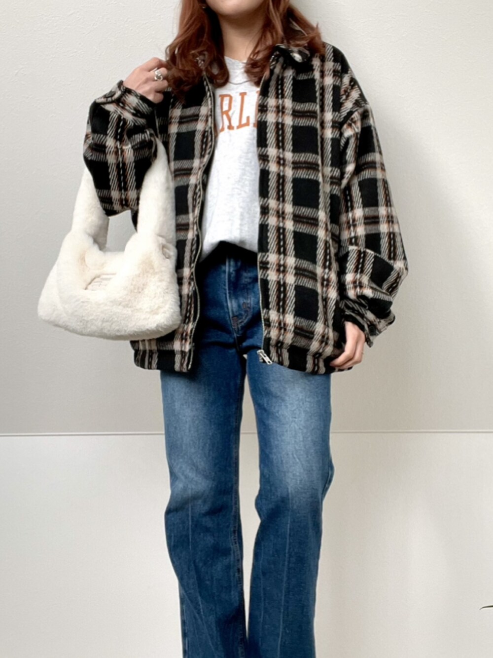 ブラック系のブルゾン、ブルー系のデニムパンツ、ブラック系のスニーカーを着用したレディースの冬コーディネートの2枚目の写真