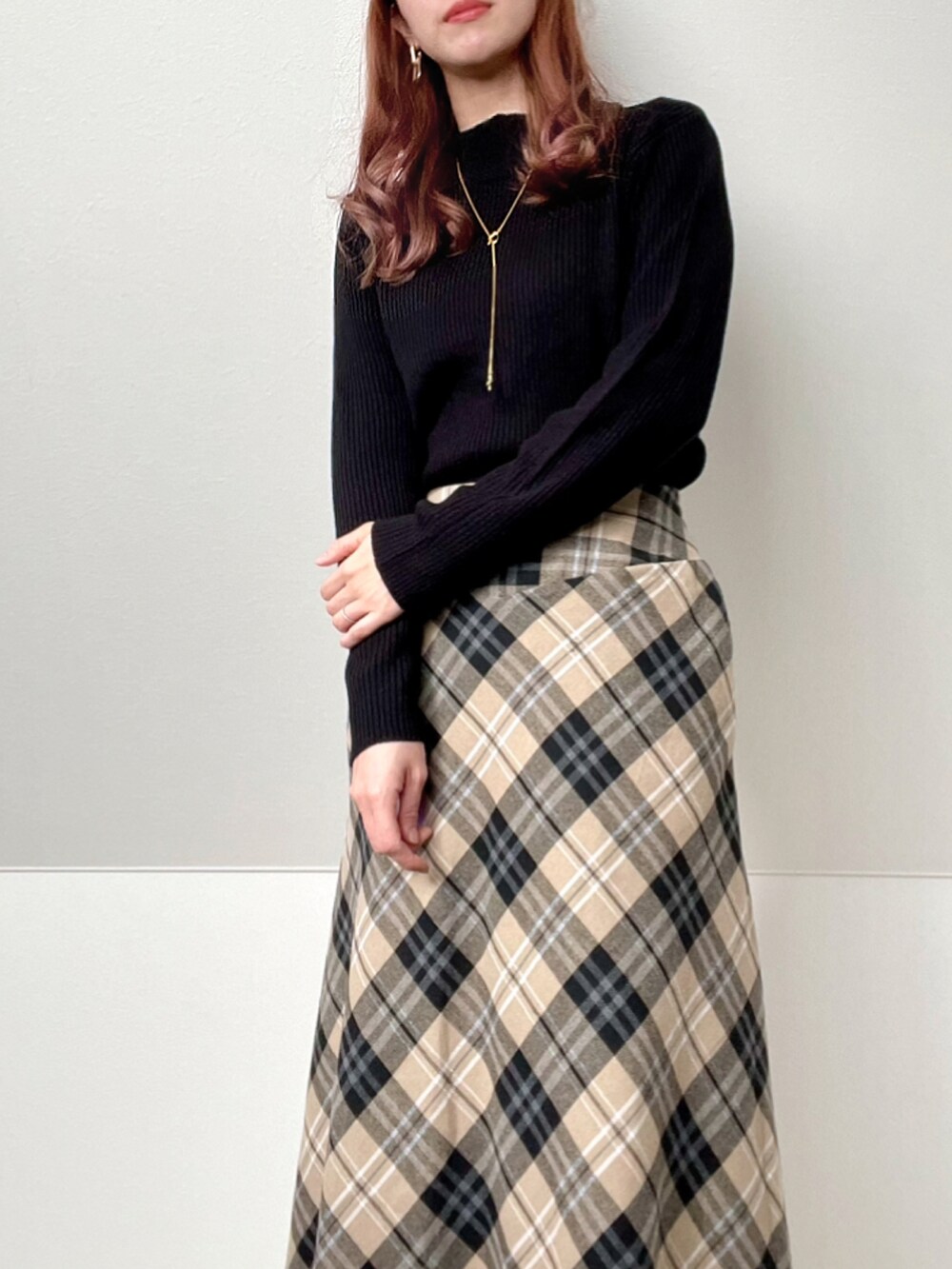 ベージュ系のスカート、ブラック系のハンドバッグ、ブラック系のブーツを着用したレディースの冬コーディネートの2枚目の写真