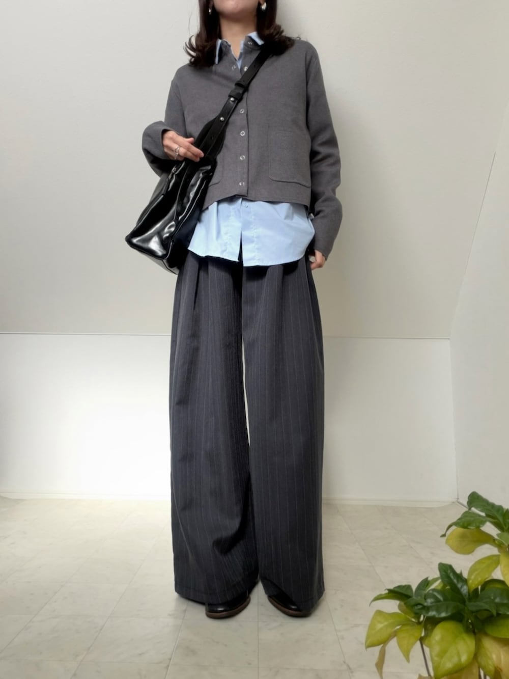 グレー系のカーディガン/ボレロ、ブラック系のショルダーバッグ、グレー系のスラックスを着用したレディースの冬コーディネートの2枚目の写真