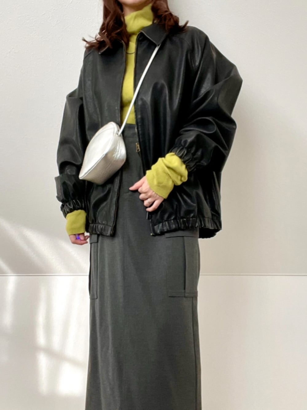 ブラック系のブルゾン、グレー系のスカート、シルバー系のショルダーバッグを着用したレディースの冬コーディネートの2枚目の写真