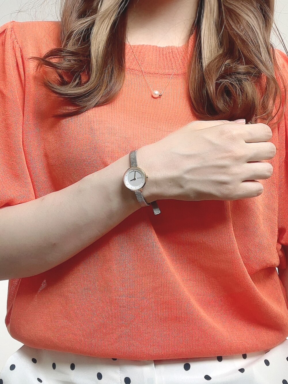 オレンジ系のニット/セーター、ブラック系のサンダル、ホワイト系のパンツを着用したレディースの夏コーディネートの2枚目の写真