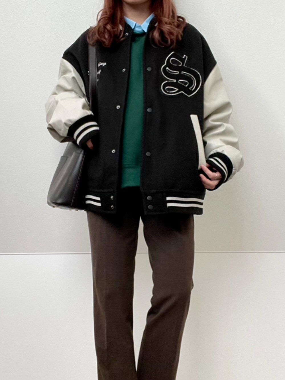 ブラック系のスタジャン、ブラウン系のローファー、ブラウン系のスラックスを着用したレディースの冬コーディネートの2枚目の写真