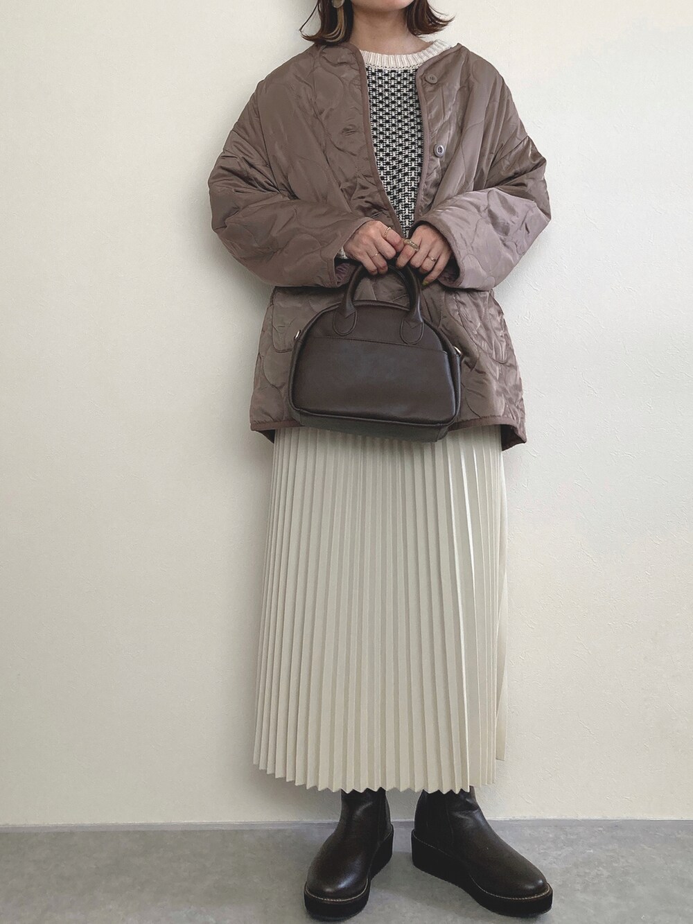 ブラウン系のノーカラーコート、ブラウン系のブーツを着用したレディースの冬コーディネートの3枚目の写真