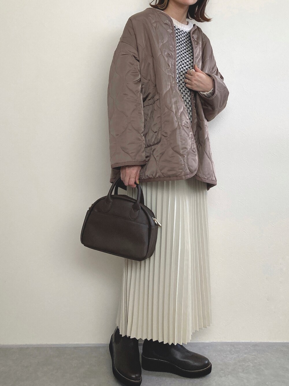 ブラウン系のノーカラーコート、ブラウン系のブーツを着用したレディースの冬コーディネートの4枚目の写真