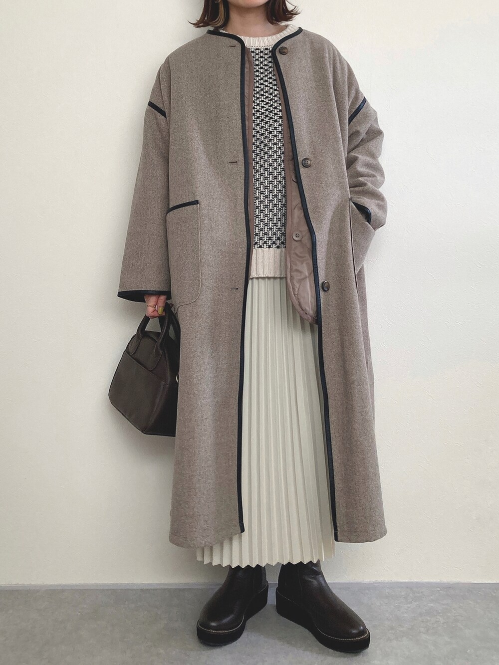 ブラウン系のノーカラーコート、ブラウン系のブーツを着用したレディースの冬コーディネートの2枚目の写真