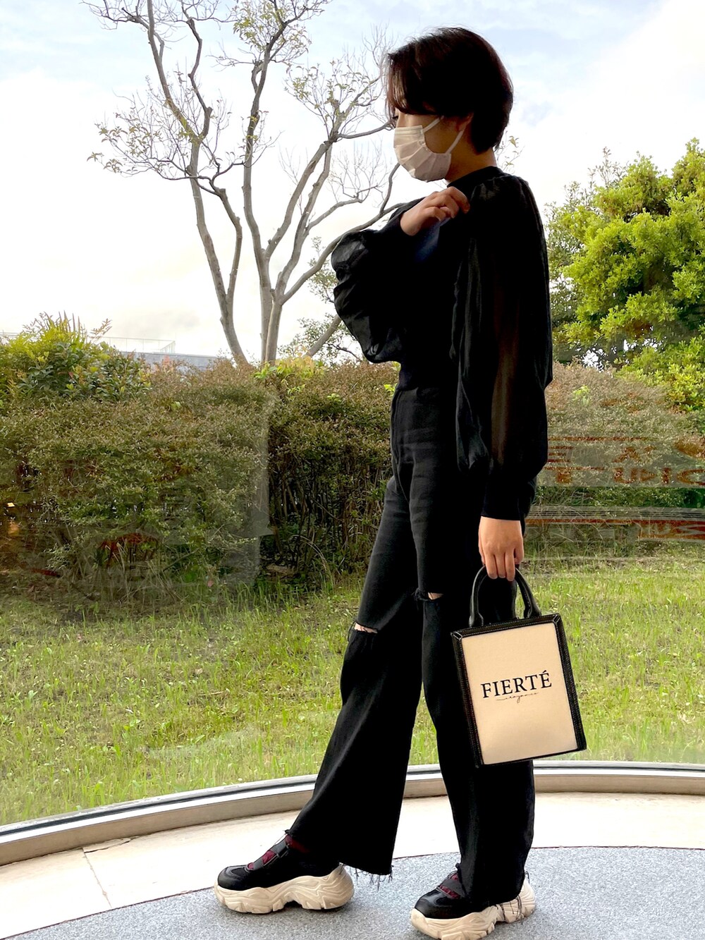 ブラック系のアンサンブル、ブラック系のデニムパンツ、ブラック系のショルダーバッグを着用したレディースの春コーディネートの2枚目の写真