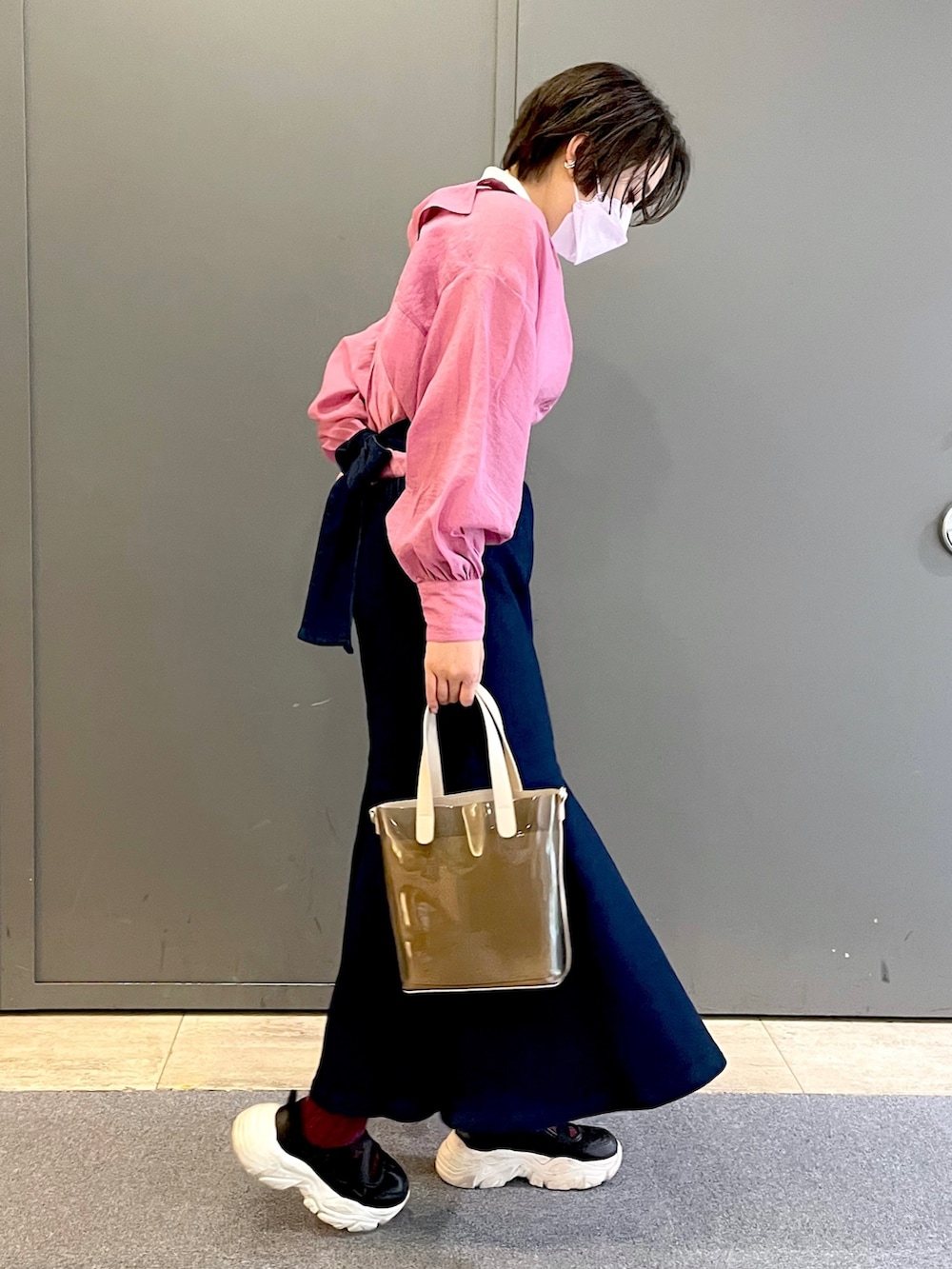 ピンク系のシャツ/ブラウス、ブルー系のスカート、ブラック系のスニーカーを着用したレディースの春コーディネートの2枚目の写真