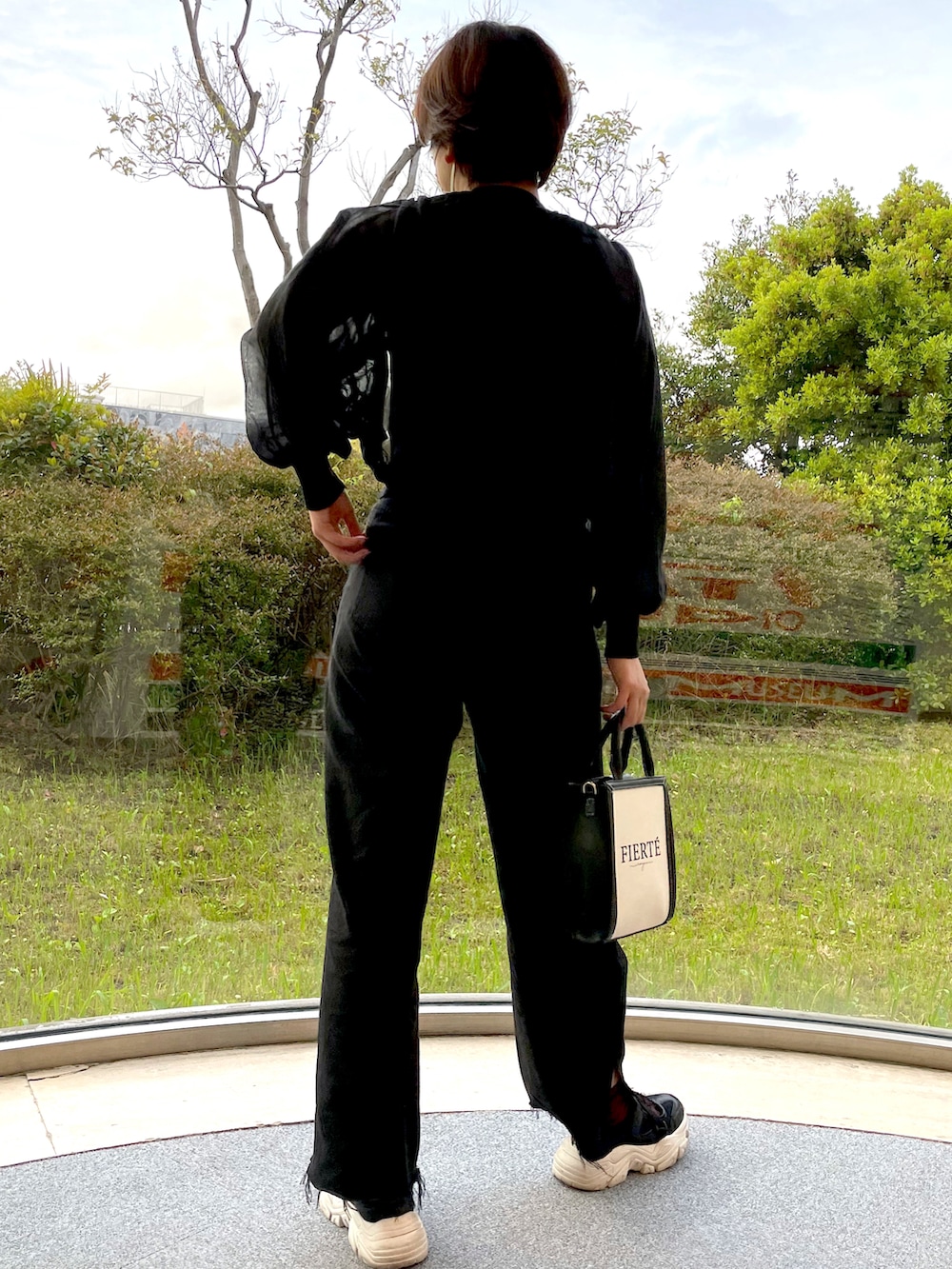 ブラック系のアンサンブル、ブラック系のデニムパンツ、ブラック系のショルダーバッグを着用したレディースの春コーディネートの4枚目の写真