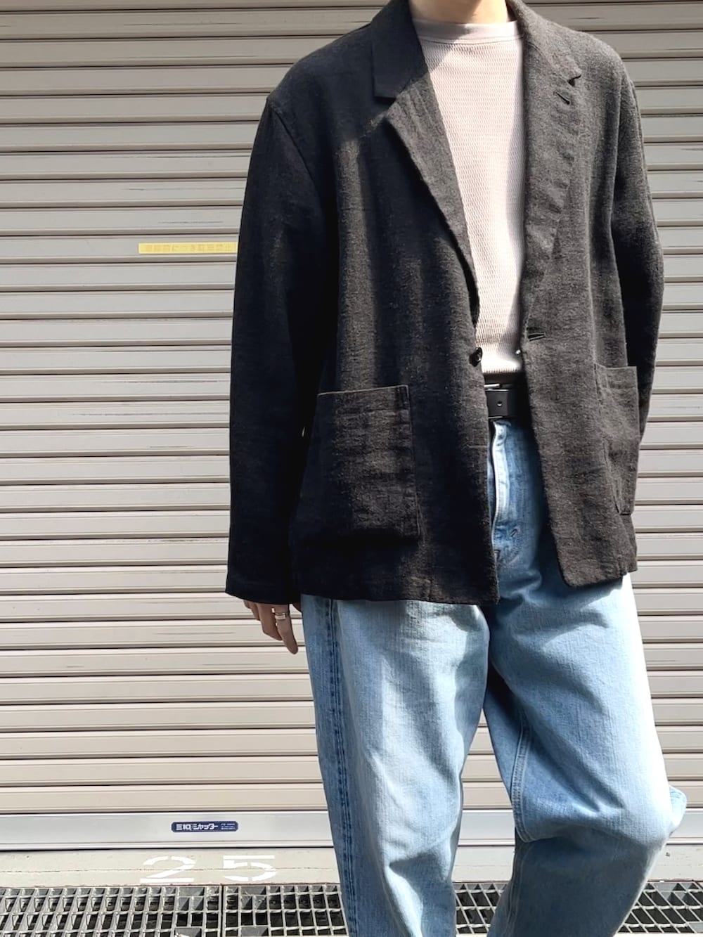 ブラック系のテーラードジャケット、ベージュ系のTシャツ/カットソー、ブルー系のデニムパンツを着用したメンズの春コーディネートの2枚目の写真