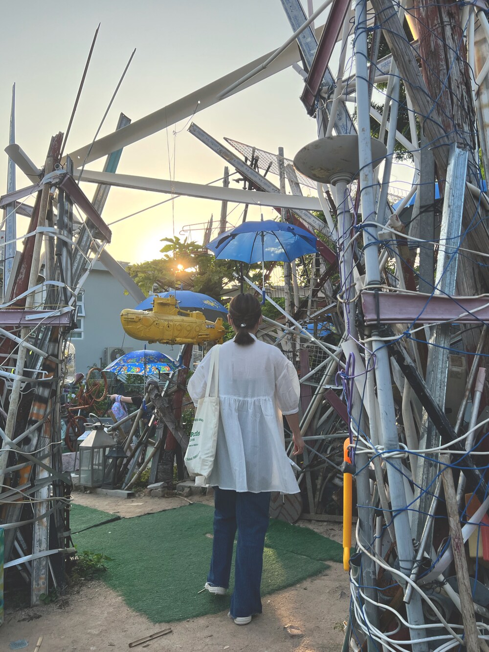 ホワイト系のトップス、グリーン系のタンクトップ、ブルー系のデニムパンツを着用したレディースの春コーディネートの2枚目の写真